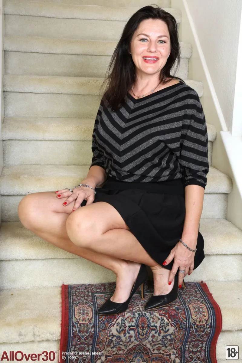 Голая пожилая тётя эротично позирует на лестнице